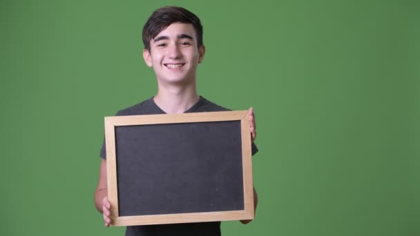 Jonge knappe Iraanse tiener jongen tegen groene achtergrond — Stockvideo