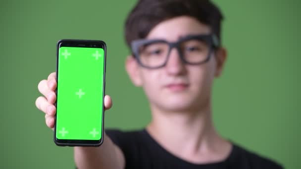 Young handsome Iranian teenage boy against green background — Stock Video