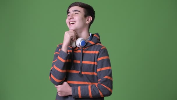 Young handsome Iranian teenage boy against green background — Stock Video