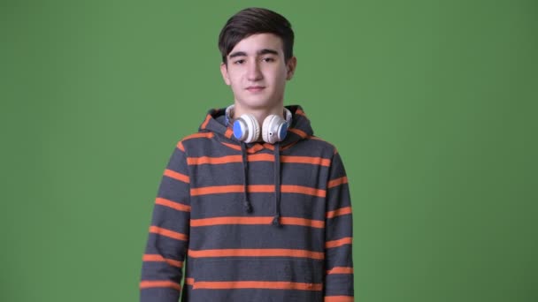 Mladý pohledný íránské dospívající chlapec proti zeleným pozadím — Stock video