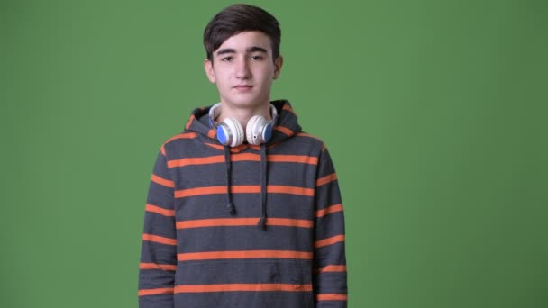年轻英俊的伊朗少年男孩反对绿色背景 — 图库视频影像