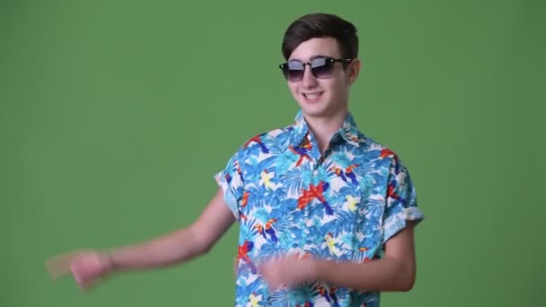 Young handsome Iranian teenage boy ready for vacation against green background — Stock Video