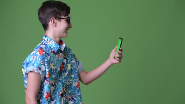 Young handsome Iranian teenage boy ready for vacation against green background — Stock Video