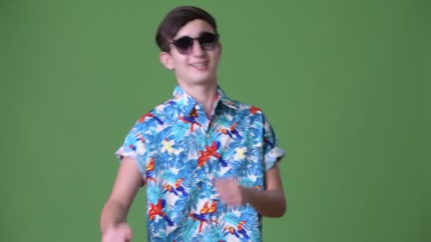 Young handsome Iranian teenage boy ready for vacation against green background — Stock Video