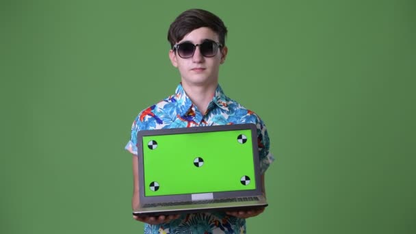 Young handsome Iranian teenage boy ready for vacation against green background — Stock Video
