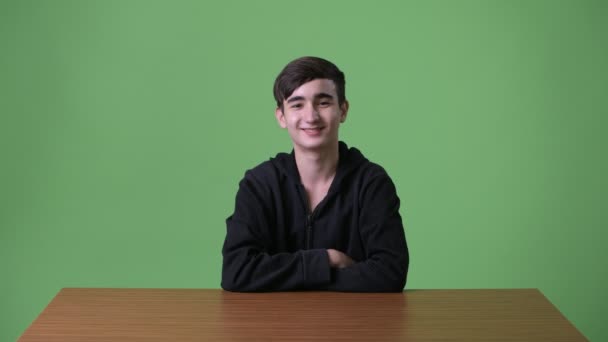 Young handsome Iranian teenage boy against green background — Stock Video