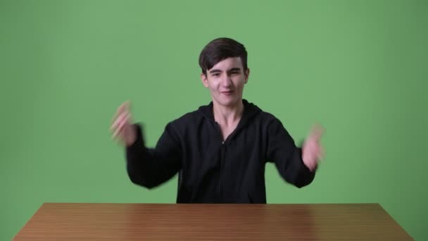 Young handsome Iranian teenage boy against green background — Stock Video