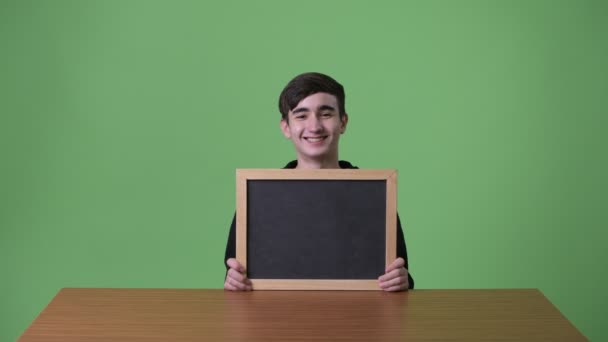 Joven guapo adolescente iraní contra fondo verde — Vídeos de Stock