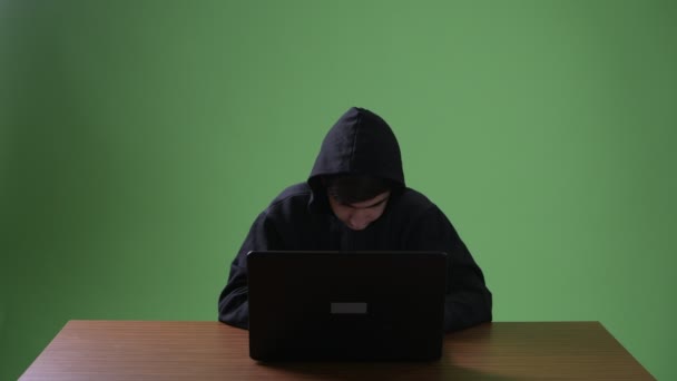 Computerhacker im Teenager-Alter vor grünem Hintergrund — Stockvideo