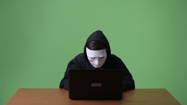 Молодой хакер-подросток на зеленом фоне — стоковое видео