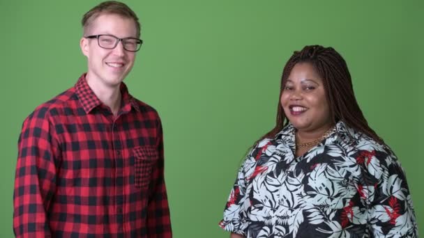 Übergewichtige Afrikanerin und junger skandinavischer Mann gemeinsam vor grünem Hintergrund — Stockvideo