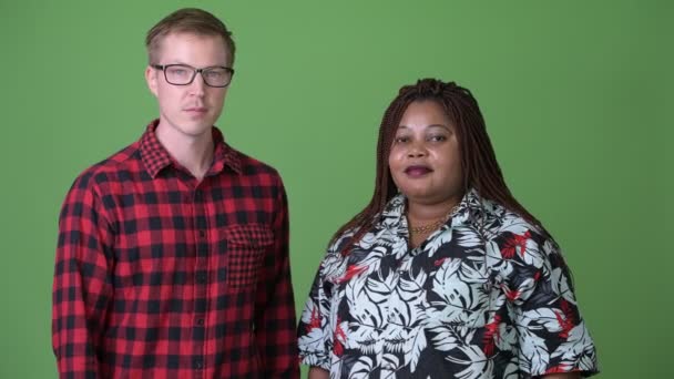Толстая африканская женщина и молодой скандинавский мужчина вместе на зеленом фоне — стоковое видео