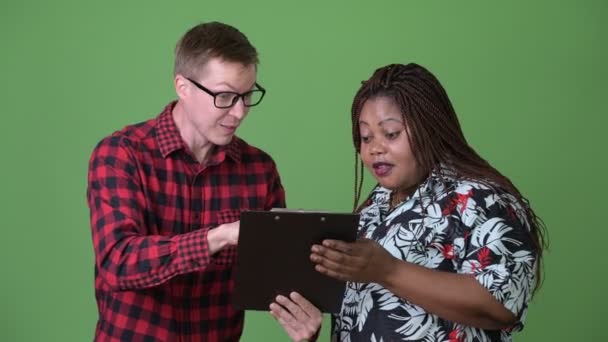 Übergewichtige Afrikanerin und junger skandinavischer Mann gemeinsam vor grünem Hintergrund — Stockvideo