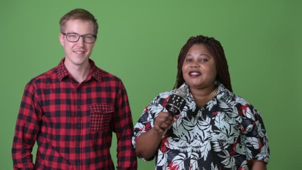 Übergewichtige Afrikanerin und junger skandinavischer Mann gemeinsam vor grünem Hintergrund — Stockvideo