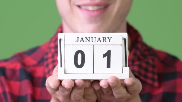 Молодой счастливый человек показывает календарь блок на зеленом фоне — стоковое видео