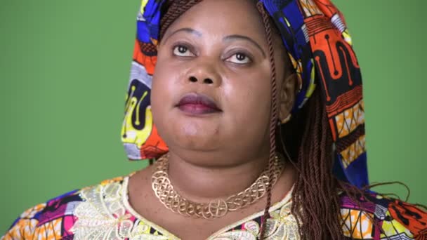 Übergewichtige schöne afrikanische Frau in traditioneller Kleidung vor grünem Hintergrund — Stockvideo