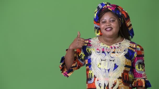 Υπέρβαροι όμορφη γυναίκα αφρικανική φορώντας παραδοσιακή ενδυμασία ενάντια σε πράσινο φόντο — Αρχείο Βίντεο