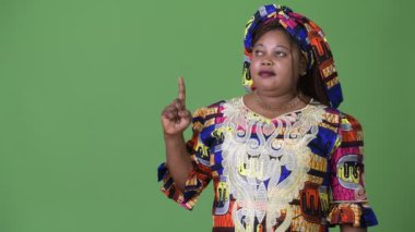 Yeşil arka plana karşı geleneksel kıyafetleri giyen güzel Afrikalı kadın kilolu