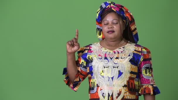 Yeşil arka plana karşı geleneksel kıyafetleri giyen güzel Afrikalı kadın kilolu — Stok video