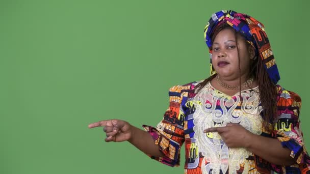 Mujer africana hermosa con sobrepeso que usa ropa tradicional sobre fondo verde — Vídeos de Stock