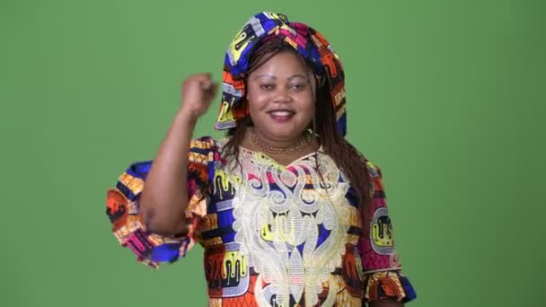 Yeşil arka plana karşı geleneksel kıyafetleri giyen güzel Afrikalı kadın kilolu — Stok video