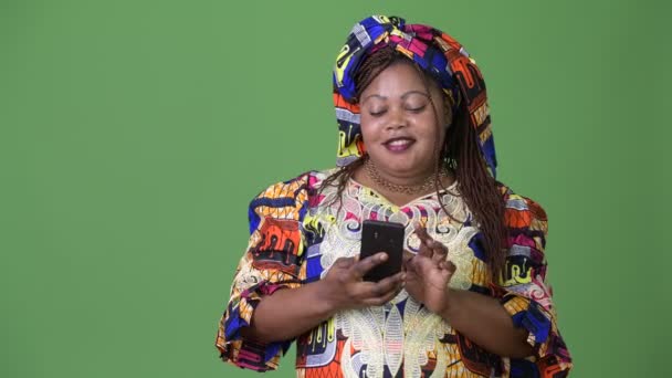 超重的美丽的非洲妇女穿着传统服装反对绿色背景 — 图库视频影像