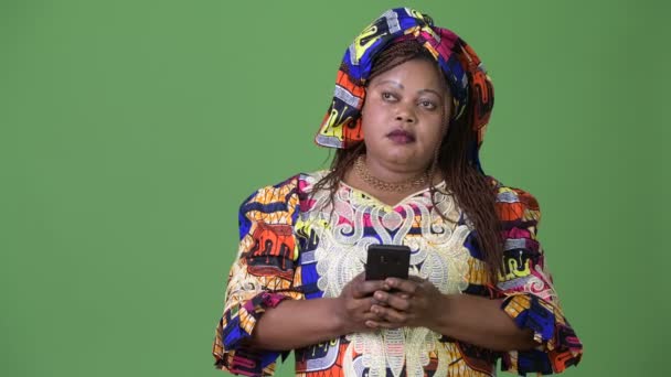 Übergewichtige schöne afrikanische Frau in traditioneller Kleidung vor grünem Hintergrund — Stockvideo