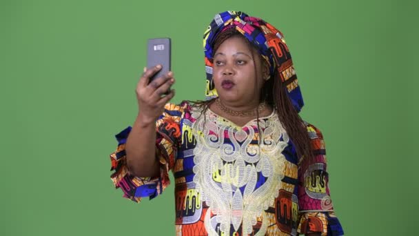 Mujer africana hermosa con sobrepeso que usa ropa tradicional sobre fondo verde — Vídeo de stock