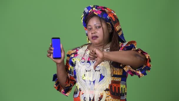 Overweight beautiful African woman wearing traditional clothing against green background — Stock Video