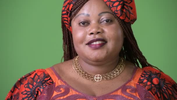 Overweight beautiful African woman wearing traditional clothing against green background — Stock Video