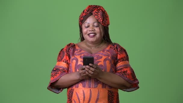 Толстая красивая африканская женщина в традиционной одежде на зеленом фоне — стоковое видео