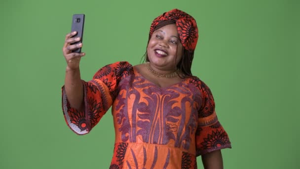 Overgewicht mooie Afrikaanse vrouw dragen traditionele kleding tegen groene achtergrond — Stockvideo
