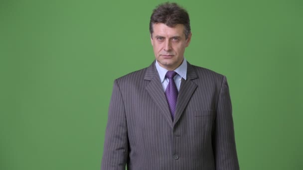 Reifer gutaussehender Geschäftsmann vor grünem Hintergrund — Stockvideo