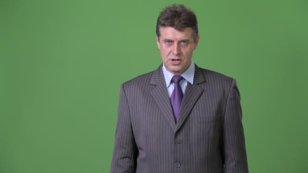 Mature handsome businessman against green background — Stock Video
