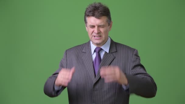 Volwassen knappe zakenman tegen groene achtergrond — Stockvideo