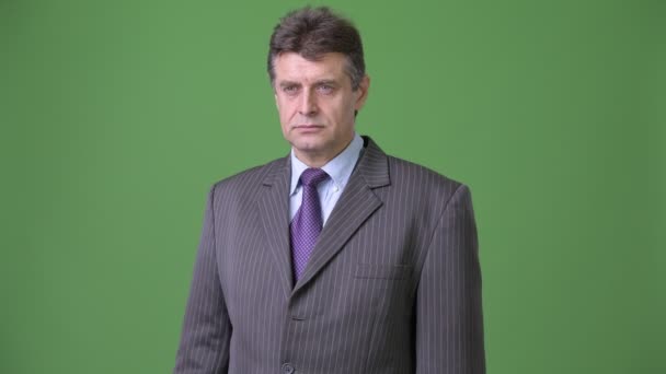 Mature handsome businessman against green background — Stock Video