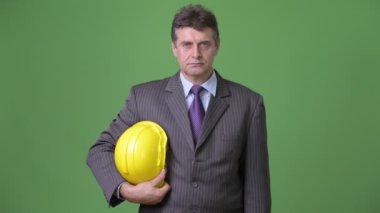 Olgun yakışıklı işadamı yeşil bir arka plana dayanır