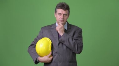 Olgun yakışıklı işadamı yeşil bir arka plana dayanır