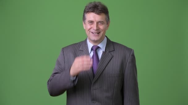Reifer gutaussehender Geschäftsmann vor grünem Hintergrund — Stockvideo