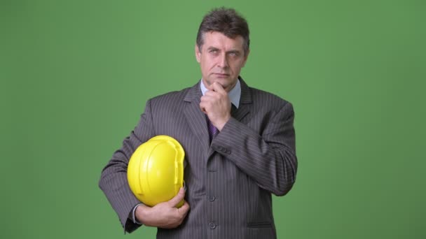 Mature handsome businessman against green background — Stock Video