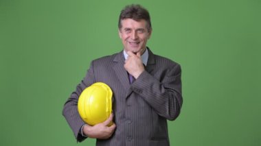 Olgun yakışıklı işadamı yeşil bir arka plana dayanır