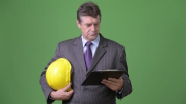 Olgun yakışıklı işadamı yeşil bir arka plana dayanır