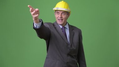 Olgun yakışıklı işadamı yeşil bir arka plana dayanır