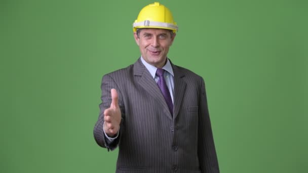 Mature handsome businessman against green background — Stock Video