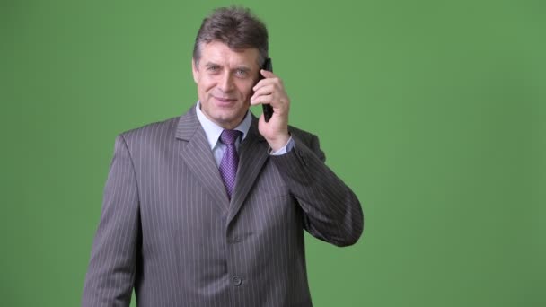 Mature handsome businessman against green background — Stock Video