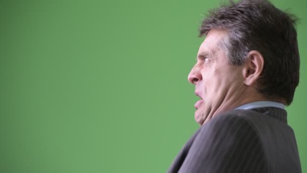 Mature handsome businessman against green background — Stock Video