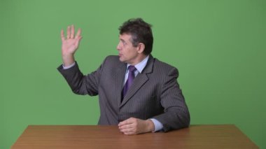 Olgun yakışıklı işadamı yeşil bir arka plana dayanır