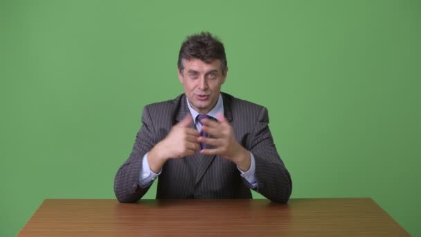 Volwassen knappe zakenman tegen groene achtergrond — Stockvideo