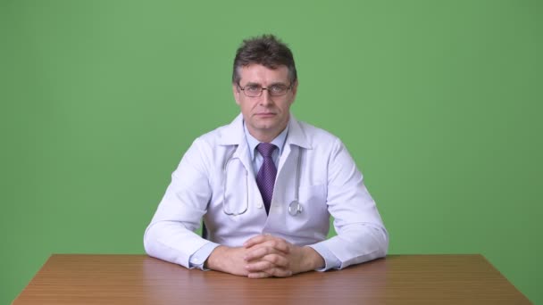 成熟英俊的男子医生反对绿色背景 — 图库视频影像