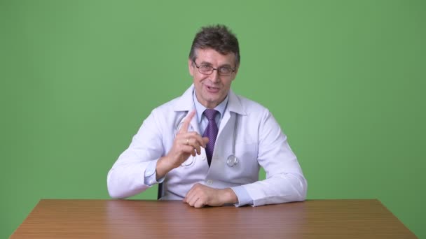 Äldre stilig man läkare mot grön bakgrund — Stockvideo